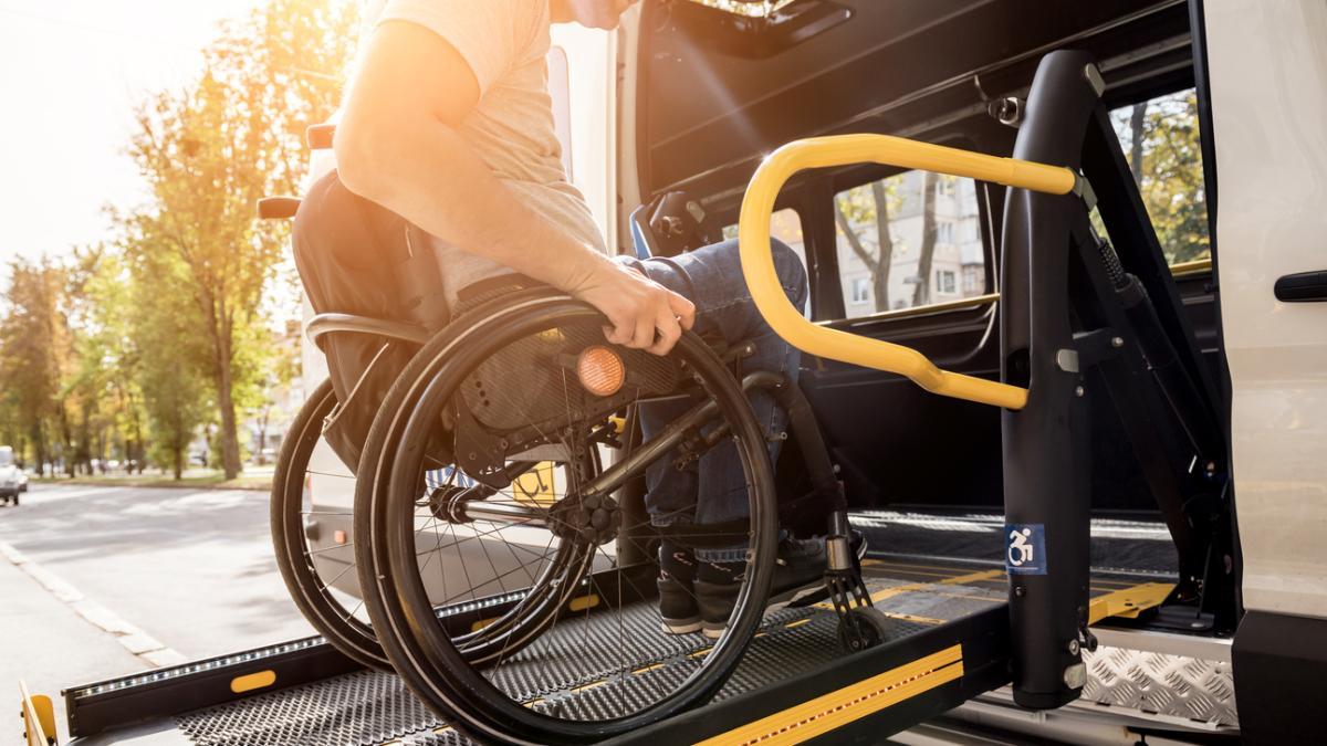 A man in a wheelchair on a lift of a vehicle